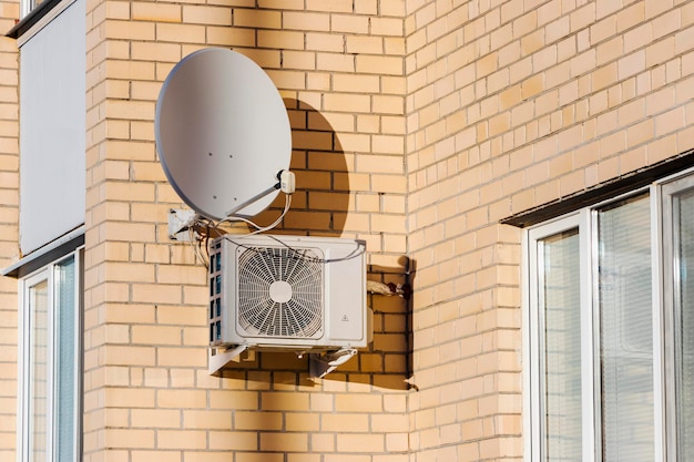 Foto um sistema de ar condicionado instalado no exterior na parede de um edifício de tijolos antena parabólica ventilação e ar condicionado do sinal de tv da habitação