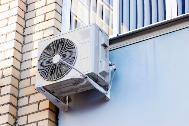 Um sistema de ar condicionado instalado no exterior na parede de um edifício de tijolos Ventilação e ar condicionado da habitação