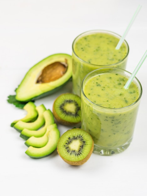 Um smoothie preparado na hora de abacate, banana, laranja, limão e kiwi em uma mesa branca. Faça dieta comida vegetariana. Alimentos crus.