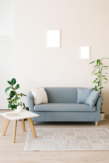 Um sofá azul empoeirado com almofadas uma mesa de café branca com plantas em uma sala de estar brilhante e aconchegante