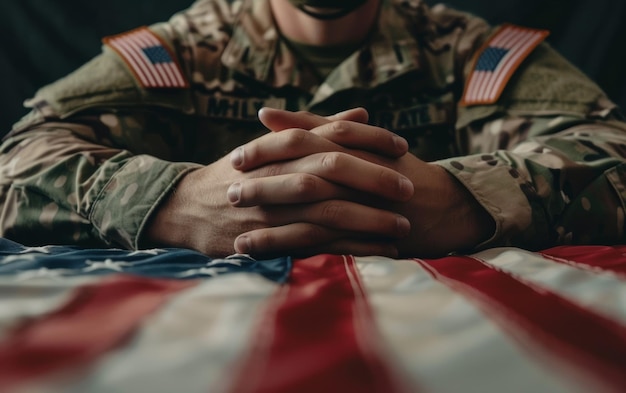 Um soldado em traje de camuflagem descansa as mãos sobre uma bandeira dos Estados Unidos transmitindo contemplação e reverência pelo Dia da Memória