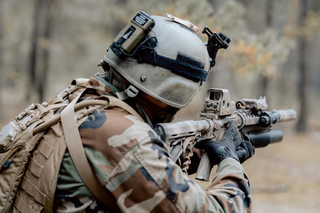 Um soldado em um uniforme militar especial com um capacete na cabeça e com um rifle sniper no para