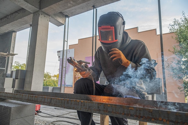 Um soldador de trabalho faz uma estrutura metálica em uma nova infraestrutura de construção