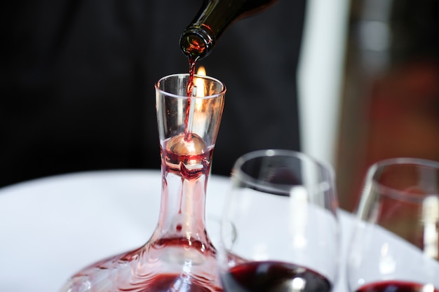 Um sommelier derramando vinho tinto na garrafa