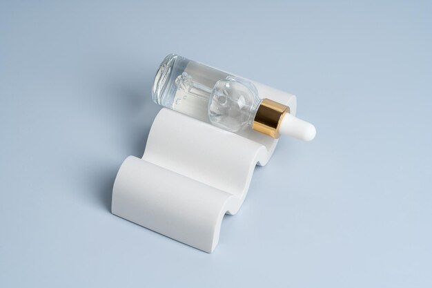Um soro ou gel transparente num frasco de gotícula num pódio branco comercialização de apresentação de produtos