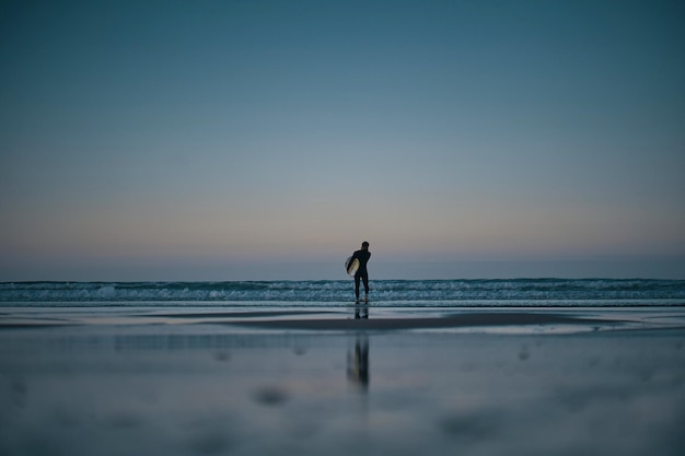 Um surfista está na água com sua prancha na frente dele.