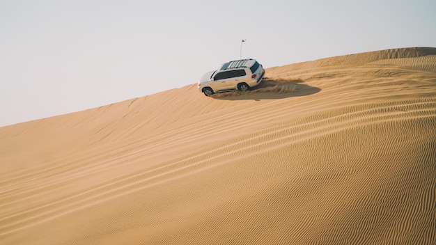 Um SUV prateado dirigindo em uma duna de areia no deserto