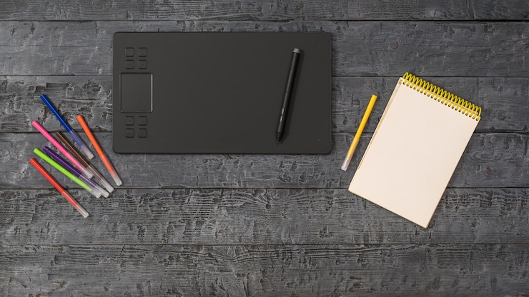 Foto um tablet gráfico, um conjunto de marcadores e um notebook em uma mesa de madeira. um dispositivo para trabalhar em editores de imagem.