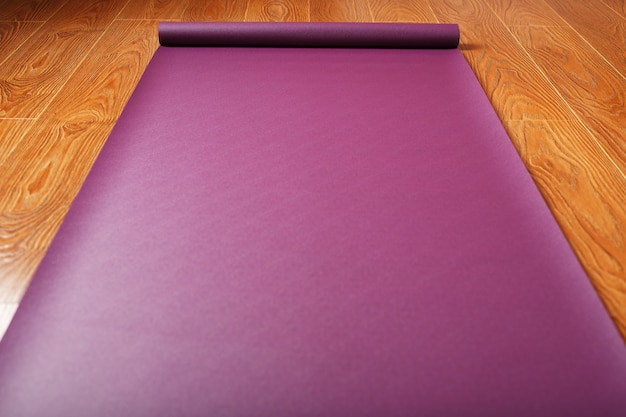Foto um tapete de ioga lilás está estendido no chão de madeira com uma estatueta de ganapati