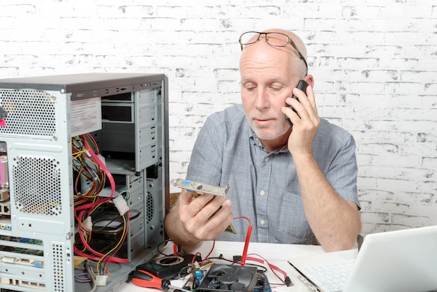 Um técnico consertando um computador e telefone