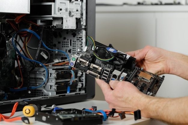 Um técnico está segurando a placa-mãe em uma caixa de mesa.