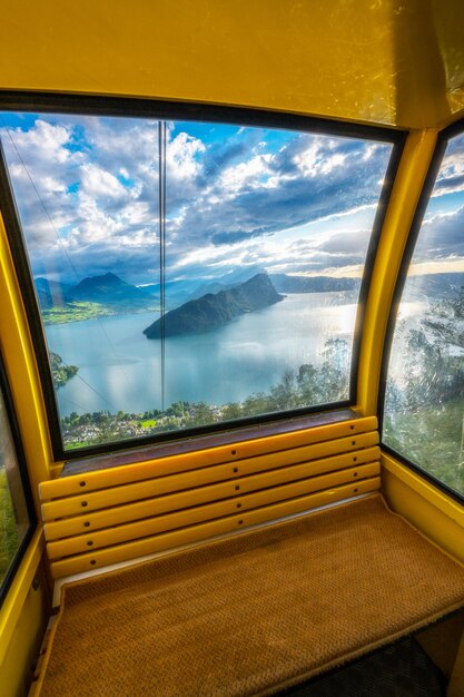 Um teleférico fotografado de dentro da vista da janela você vê um lago com montanhas