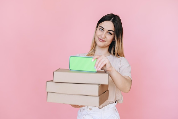 Um telefone com uma tela verde acima das caixas nas mãos da garota no fundo entrega rápida de pizza online