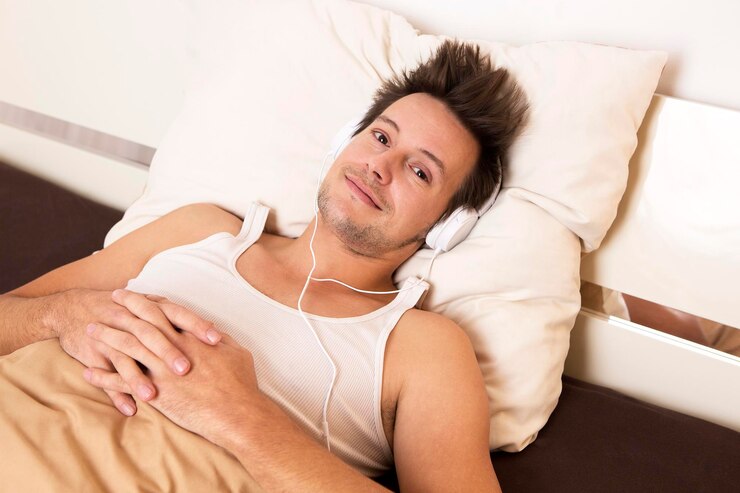 Foto um tipo esperto de camisa branca deita-se na cama e ouve música.