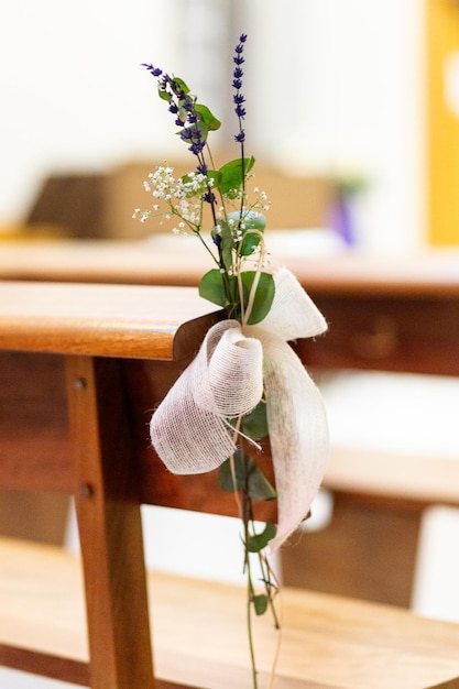 Foto um tiro vertical de uma decoração de flores de casamento amarrada em uma cadeira de madeira