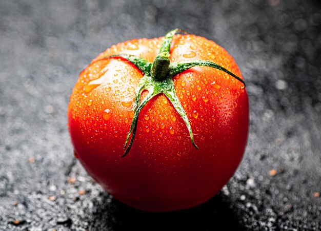 Foto um tomate maduro com gotas de água