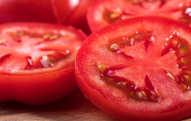 Um tomate maduro vermelho é cortado em fatias redondas em close-up