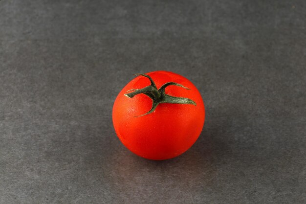 Um tomate vermelho em um fundo cinza