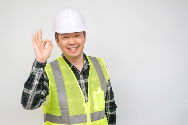 Um trabalhador asiático de meia-idade levanta a mão e assina OK.