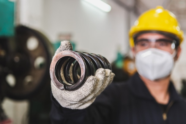 Um trabalhador asiático está verificando a qualidade da peça de metal da metalurgia da fábrica. a fabricação da peça metálica e a verificação da qualidade.