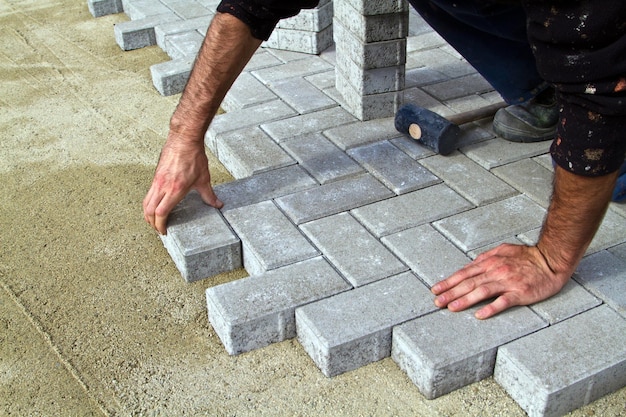 Foto um trabalhador coloca blocos de concreto para construir um terraço usando um martelo e um nível de bolha