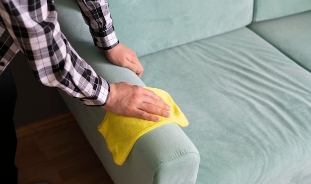 Foto um trabalhador com tecido de sofá de limpeza de pano de microfibra amarelo em casa