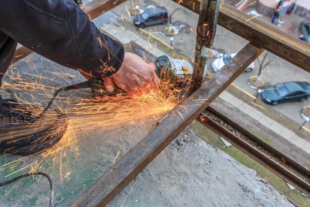 Um trabalhador corta metal com um moedor