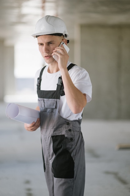 Um trabalhador da construção civil com planta falando ao telefone