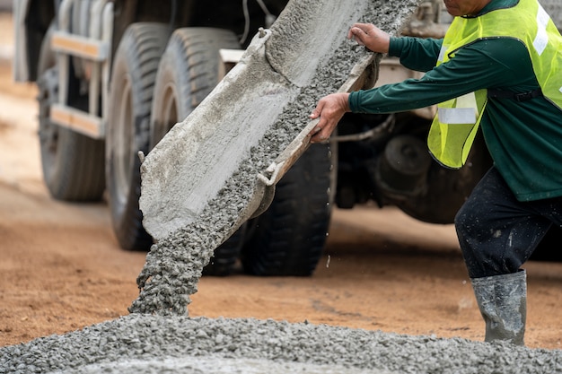 Um trabalhador da construção civil derramando um concreto molhado no local da construção de estradas