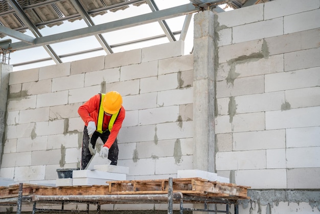 Um trabalhador da construção civil está usando argamassa adesiva para alvenaria leve no canteiro de obras