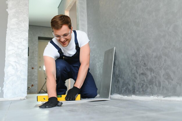 Um trabalhador da construção civil instala um grande azulejo de cerâmica