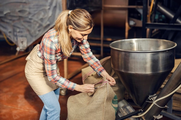 Um trabalhador da fábrica de café abrindo o saco com café e preparando-o para a moagem