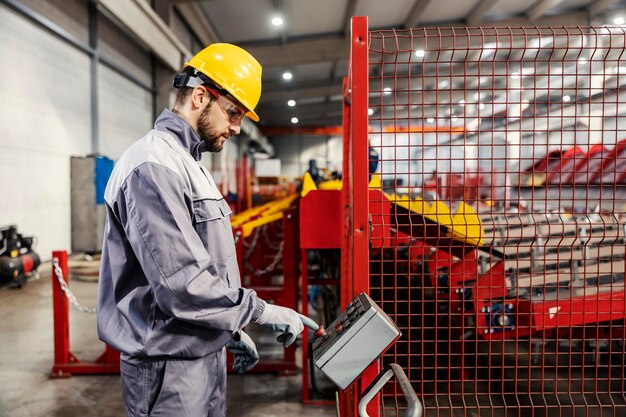 Um trabalhador da indústria metalúrgica usando o console para operar a máquina na fábrica