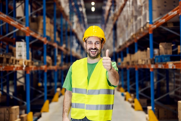 Um trabalhador de armazenamento dando sinal de positivo e sorrindo para a câmera