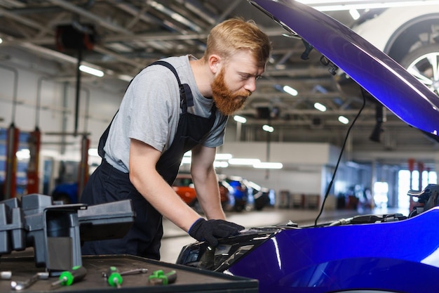 Um trabalhador de serviço de carro durante o trabalho de substituição de filtros e óleo no motor do carro Estação de serviço profissional