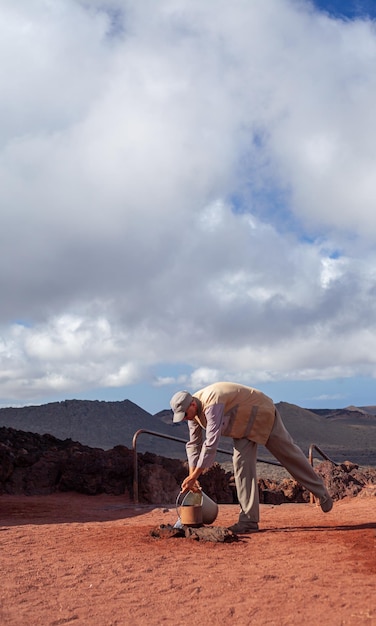 um trabalhador derrama água sobre uma falha vulcânica no Parque Nacional de Timanfaya Lanzarote Espanha