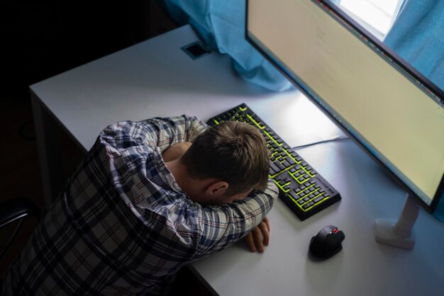 Foto um trabalhador do sexo masculino doente e cansado à noite fazendo algum trabalho no conceito de excesso de trabalho do escritório