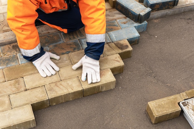 Um trabalhador em um traje de trabalho de proteção coloca lajes de pavimentação Um profissional