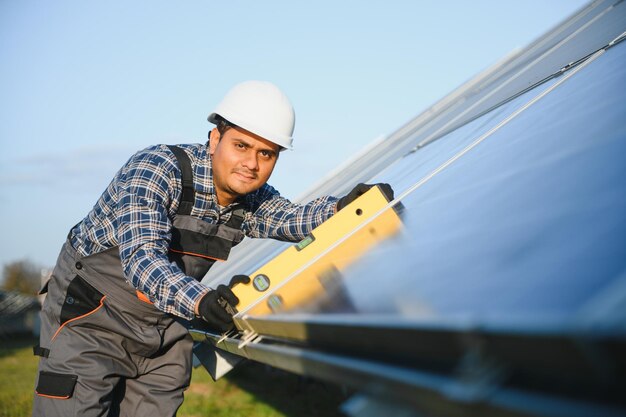 Um trabalhador indiano uniformizado e com ferramentas trabalha em uma fazenda de painéis solares