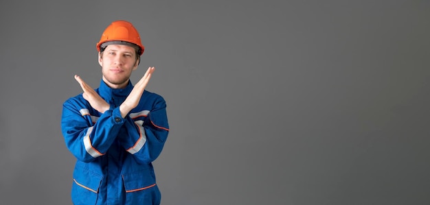 Um trabalhador masculino de uniforme azul mostrando o gesto de parada