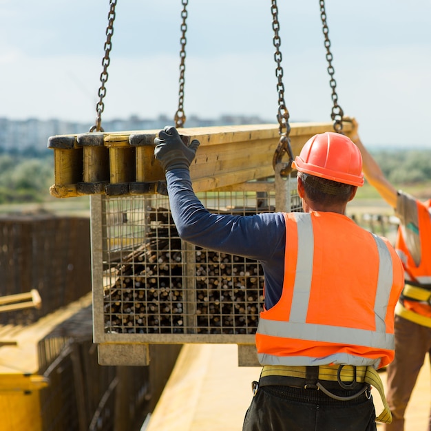 Um trabalhador pega uma carga de um guindaste de construção