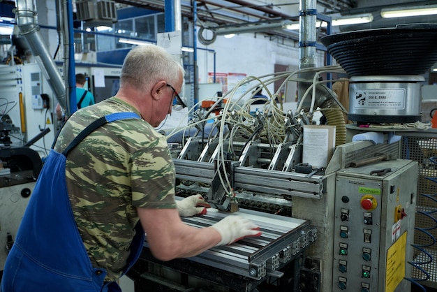 Um trabalhador processa espaços em branco de móveis em uma máquina-ferramenta em uma fábrica. Produção industrial de móveis.