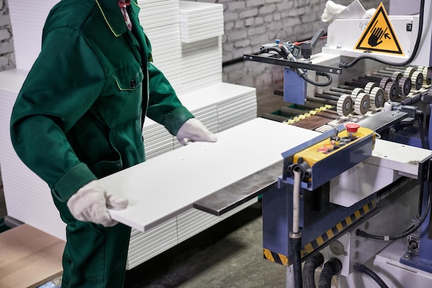 Foto um trabalhador processa peças em bruto de móveis em uma máquina tecnológica complexa em uma fábrica. produção industrial de móveis.