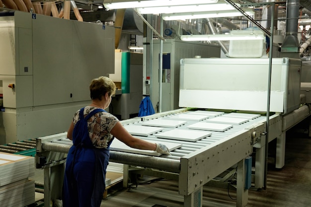 Um trabalhador processa peças em bruto de móveis em uma máquina tecnológica complexa em uma fábrica. Produção industrial de móveis.