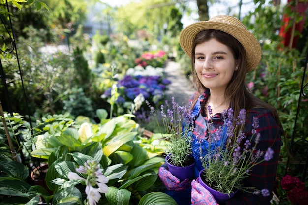 Um trabalhador segura vasos de flores de brejo em ambas as mãos na loja de jardim