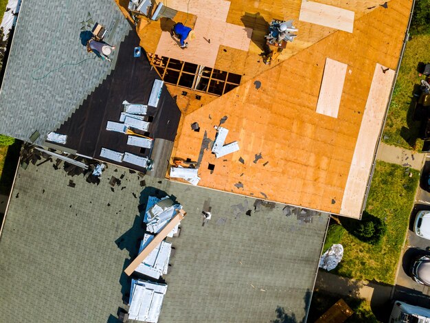 Um trabalhador substitui telhas no telhado de uma casa consertando o telhado de uma casa