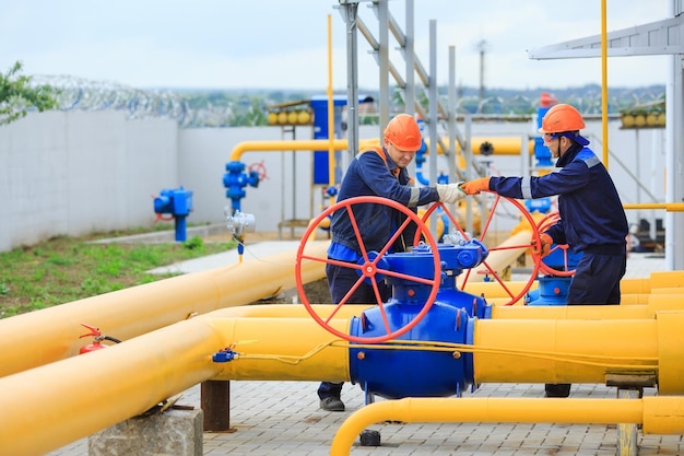 Foto um trabalhador uniformizado abre uma válvula para controlar gases