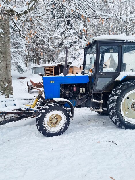Um trator azul com rodas grandes em uma floresta de neve