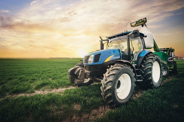 Foto um trator com um saco de fertilizante se move ao longo do campo na primavera