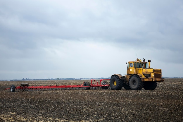 Um trator velho no campo grada colheitas de trigo